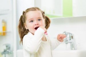 Child girl brushing teeth in bathroom